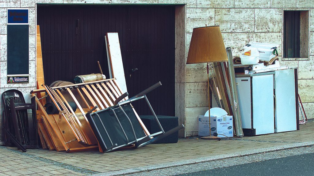 Image showing broken and dated furniture on the pavement. Items being moved in clearance service.